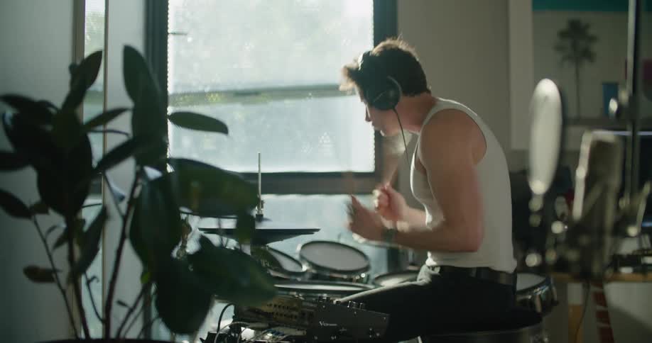 A man plays the drums indoors during the day