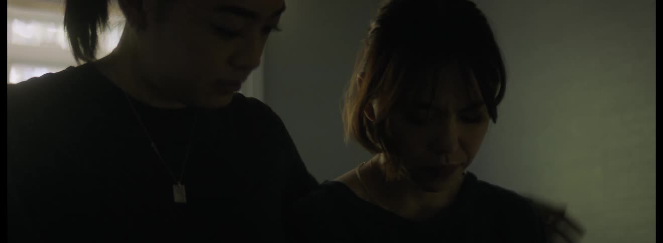 Woman looks very sad and a man sits next to her and consoles her by putting his arm around her shoulders