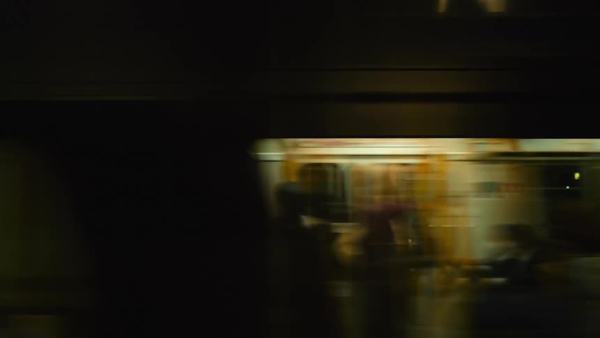 Train cars with passengers speed by at night