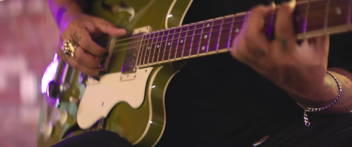 Close up of musician strumming on acoustic electric olive colored guitar