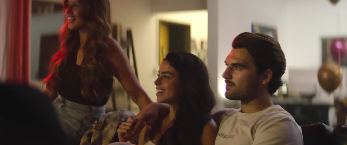 A group of friends sit at home watching something