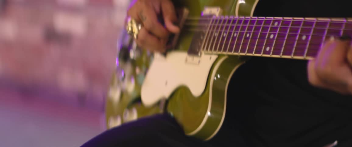 A man plays the guitar in an open room with tiled walls