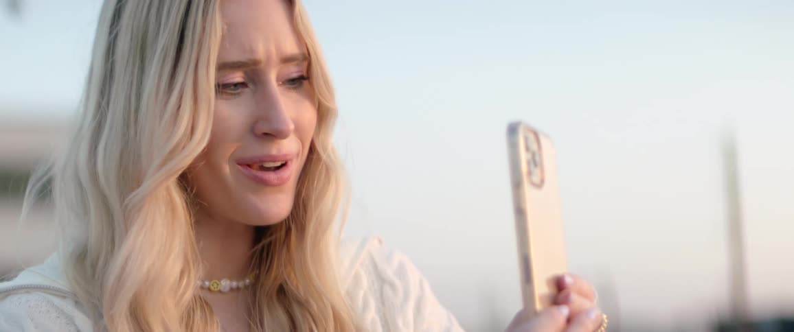 Happy blonde woman facetiming on a cell phone outdoors