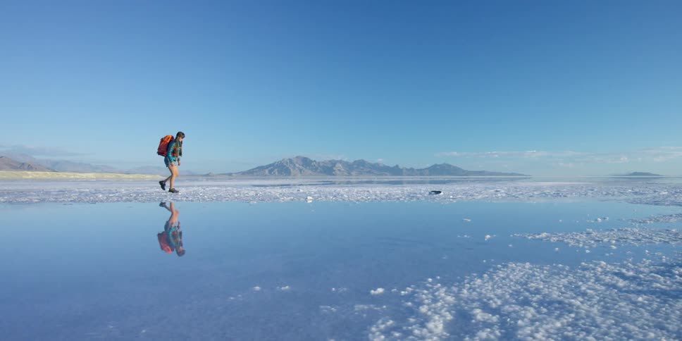 A woman walking along the edge of a body of water