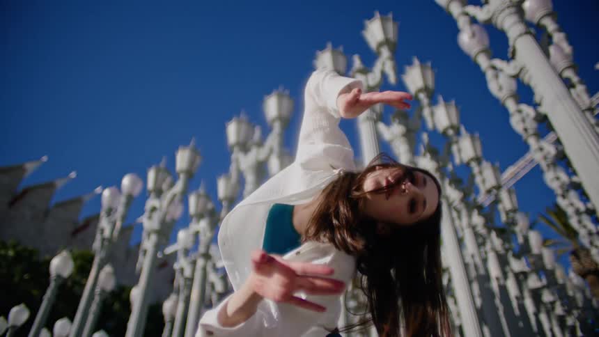 A woman dances in front of a display of lamp posts