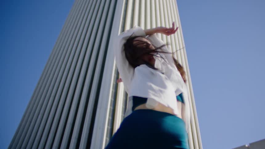 A woman is dancing outside by a tower