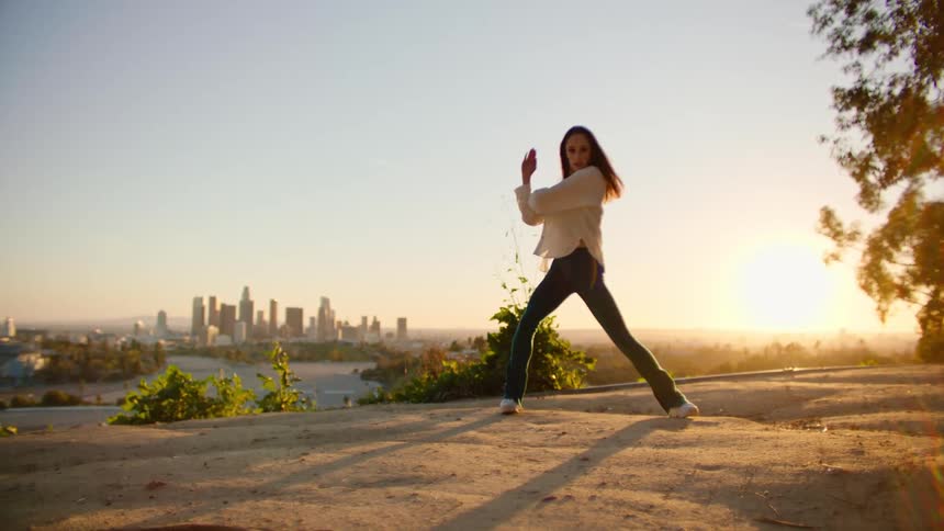 A woman is dancing on the hill by the city