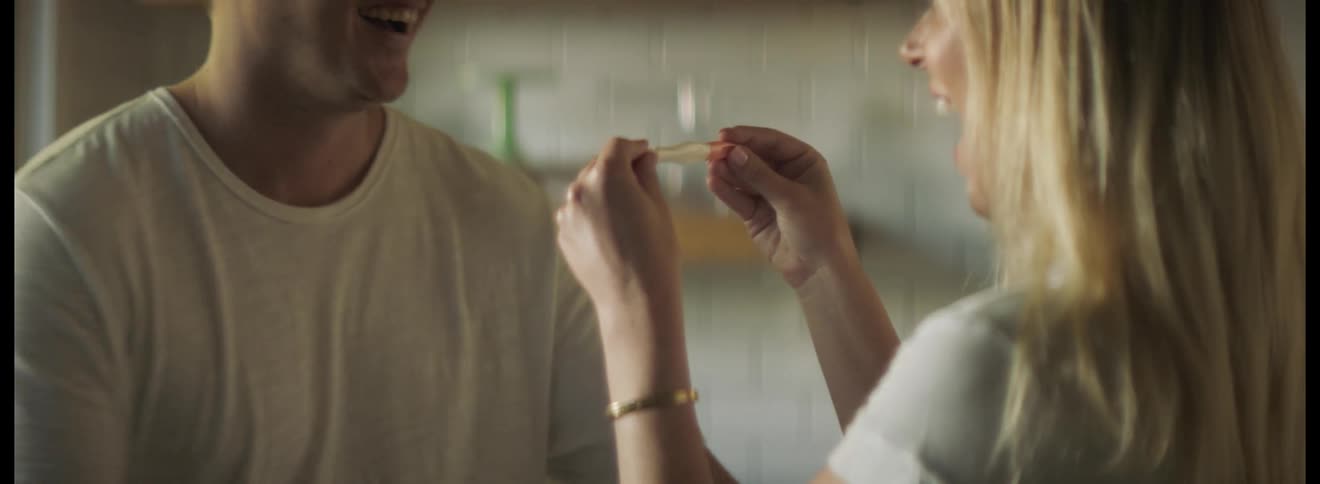 Woman surprises her partner with a pregnancy test in the kitchen at home in the morning