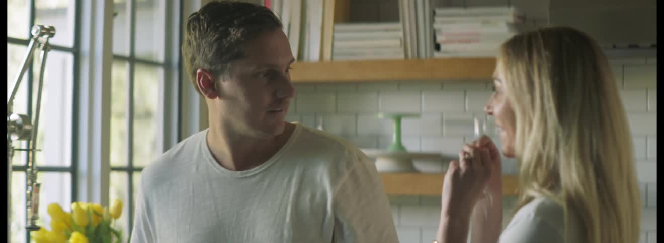 Woman runs up to her husband and shows him a pregnancy testing device and then they smile and hug