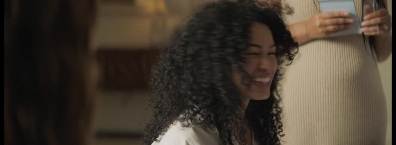 Group of female friends sitting around a table at home talking and laughing