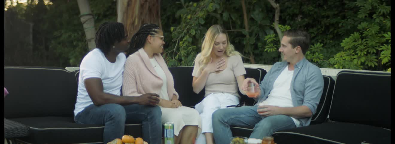 Two couples hanging out in the backyard next to a fire pit