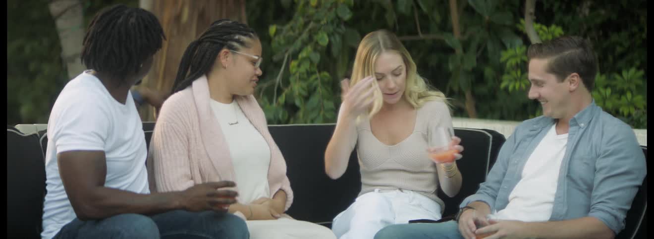 Group of friends sitting on a couch in the porch celebrate a pregnancy while drinking