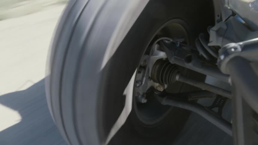 Close up of the spinning wheel of an off road vehicle driving on a gravel road at daytime
