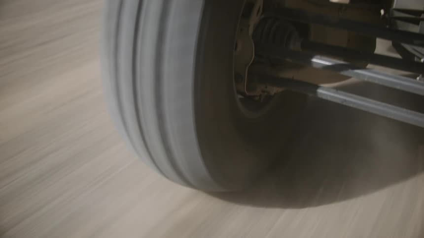 Tire on a vehicle spins rapidly as it travels on a dirt road
