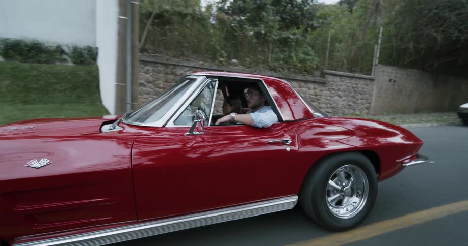 A man rides his red sports car down the road