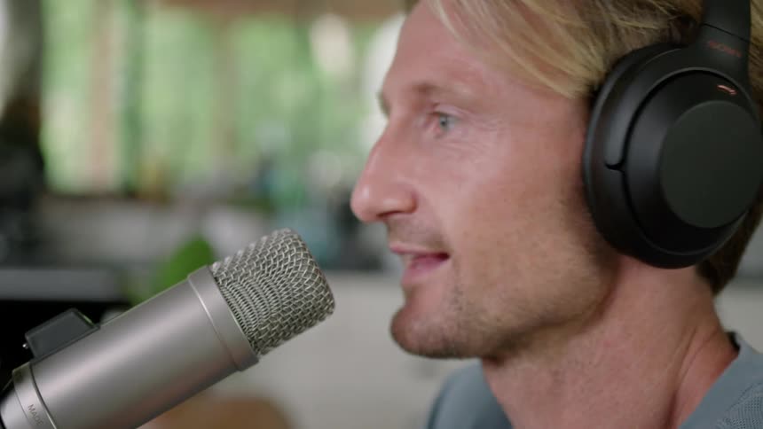 Man wearing black headphones talking on a microphone on a room at daytime