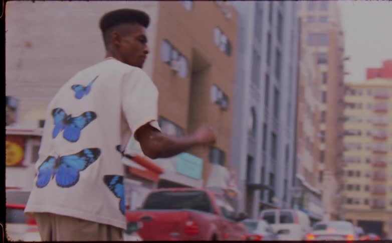 Two friends fist bump each other while riding skateboards on the city street caught on vintage film