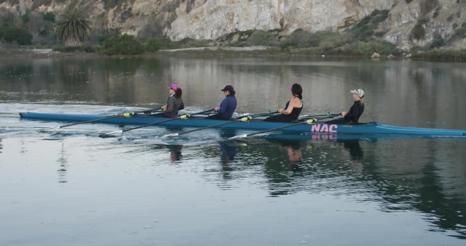 Four women row a kayak in tandem in a lake