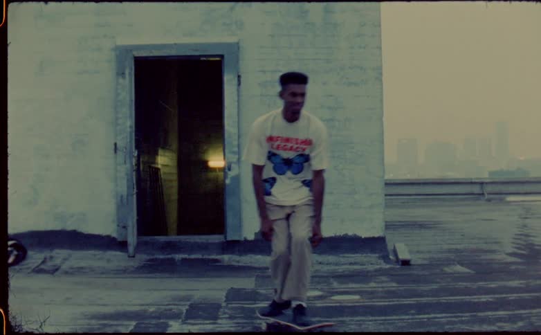 A man rides his skateboard on the rooftop of an apartment building