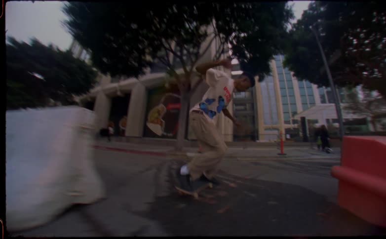 Skateboarder attempts jump as he crosses street and steps off his board as pedestrians walk nearby