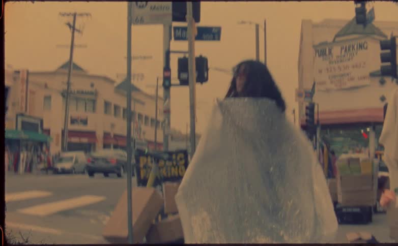 Young woman covers herself with a sparkly silver cloth while walking on the street
