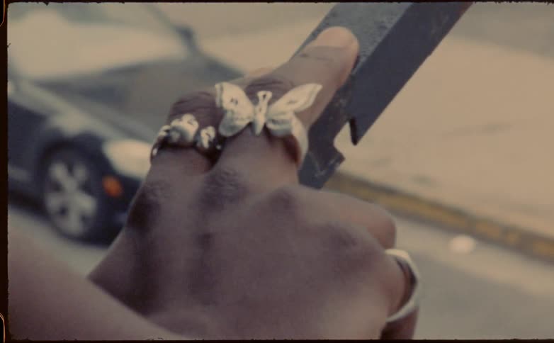 Close up of a metal butterfly ring on the finger of a woman reclined on a balcony in the city
