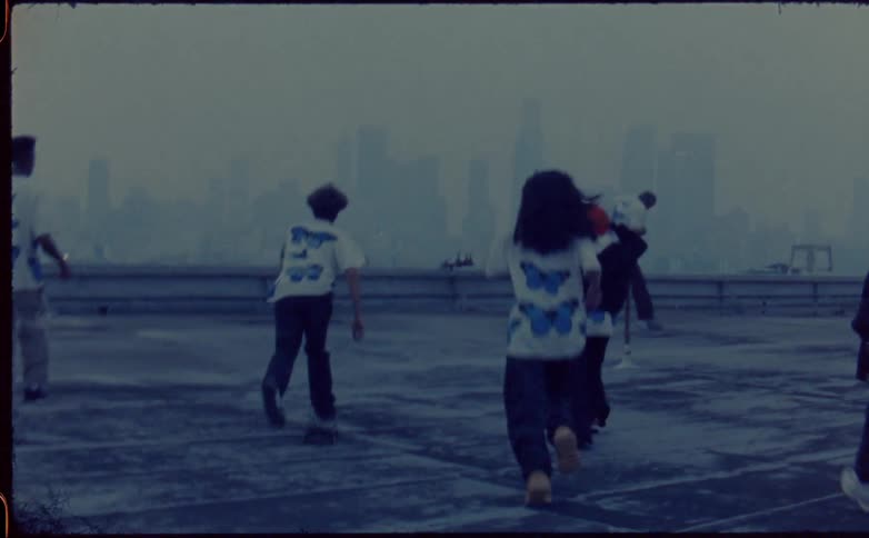 Group of friends running over the roof of a building close to the city skyline caught on vintage film