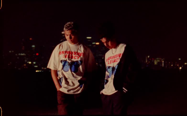 Two teenagers wearing matching shirts pose while making the same gesture