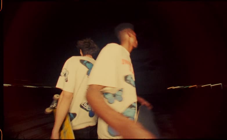 Speed up footage of two young man holding skateboards on their hands at night caught on vintage film