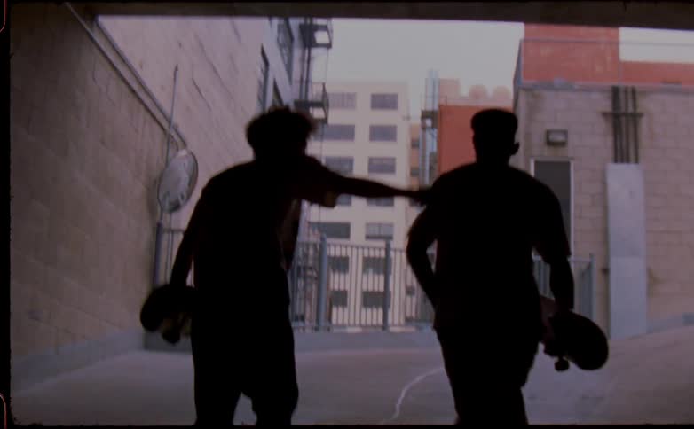 Two men walk up the ramp carrying skateboards
