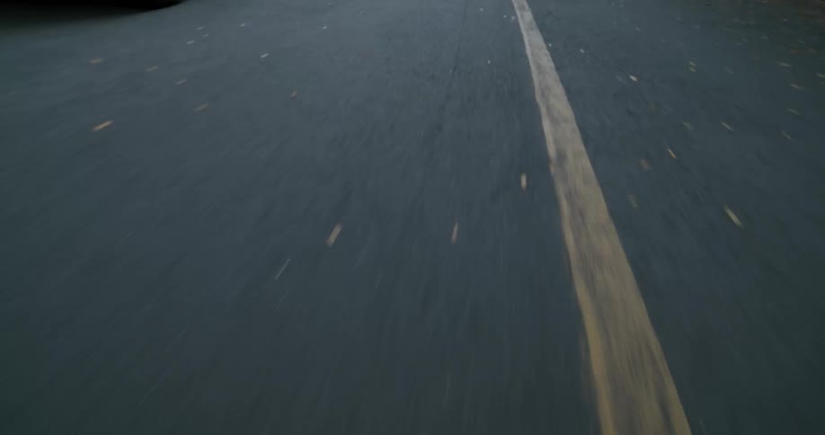 Vehicles sit parallel parked on the side of a two lane road