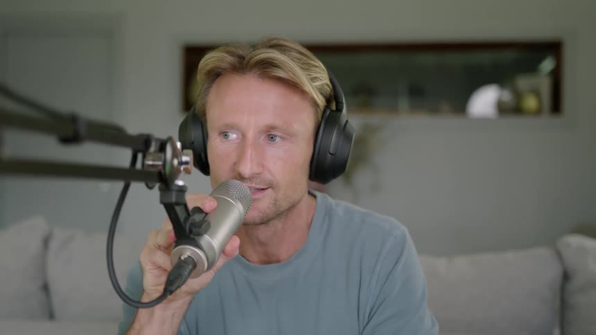 Man puts on headphones and adjusts some electronic controls then talks into a microphone