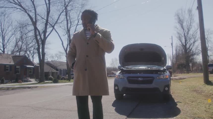 A man walking outdoors near his car