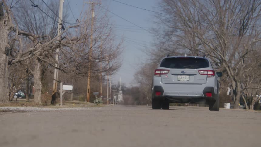 A car pulls away and drives down a neighborhood street
