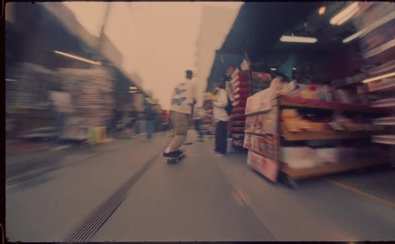 A man skateboards through a crowded outdoor market during the day