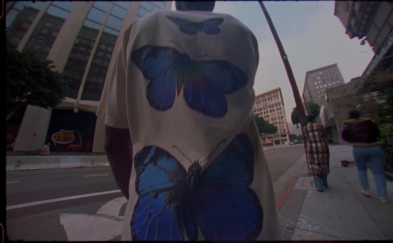A man stands on the sidewalk as two women walk past him downtown