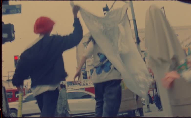 Two teenage female friends running through the street stores on a city carrying a piece of cloth