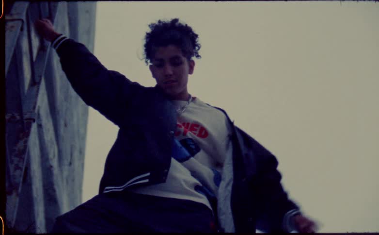 A teenage boy hangs off the ladder on a side of a building