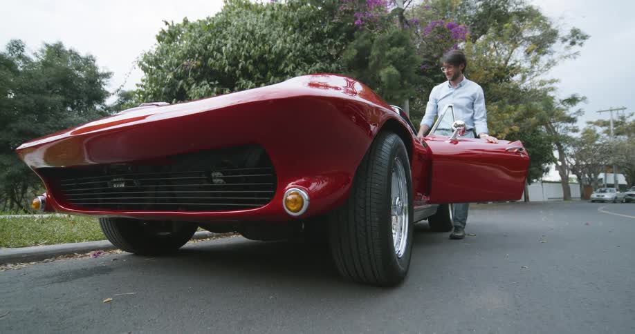 A man enters his red sports vehicle
