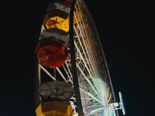 A ferris wheel is lit up and turning in a night sky