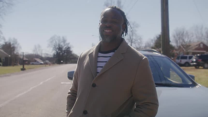 A man is smiling by his car