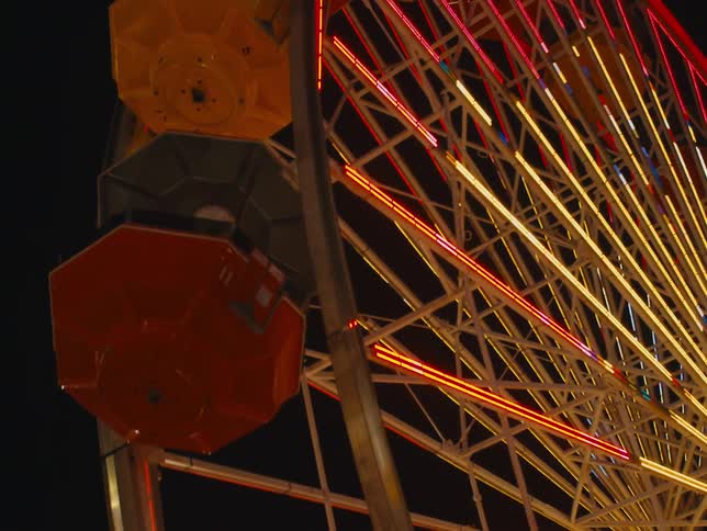 A ferris wheel is lit up and turning in a night sky