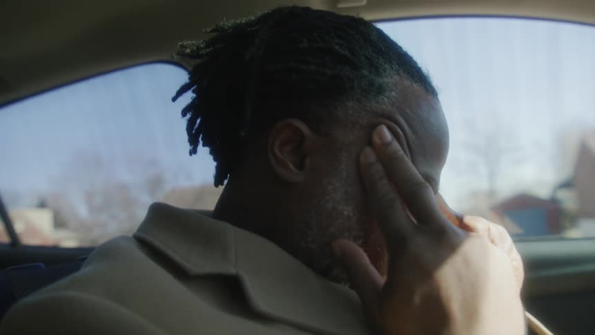 A man rubs his temples in the car