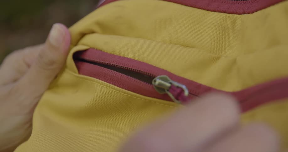 A person unzips their backpack