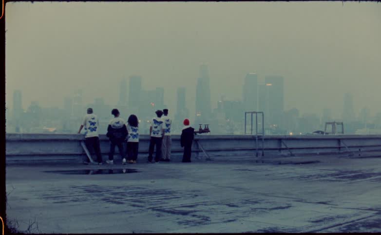 Group of friends reclined on the roof of a building next to the city skyline covered in fog