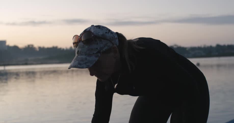 Woman wearing sunglasses on her hat inserts an oar into an oar lock on a boat in the lake