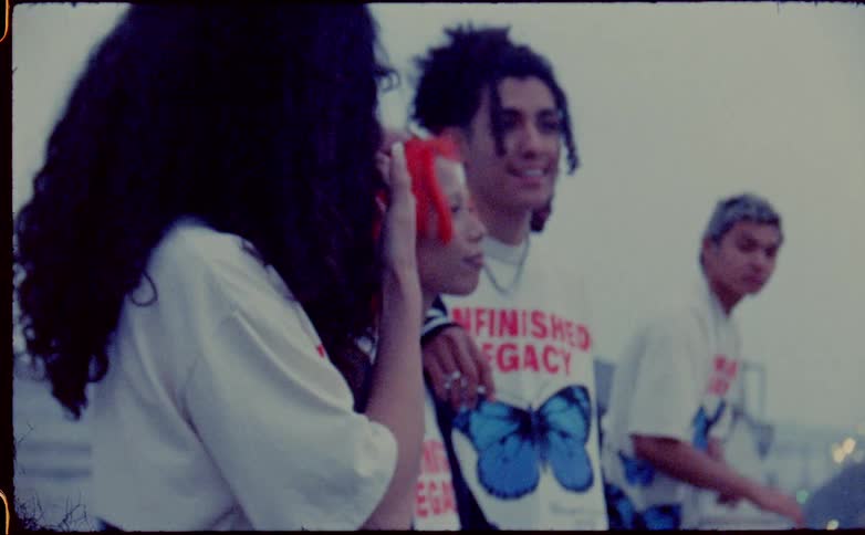 Group of men and women wearing matching shirts with a butterfly logo smile as they stand together outdoors