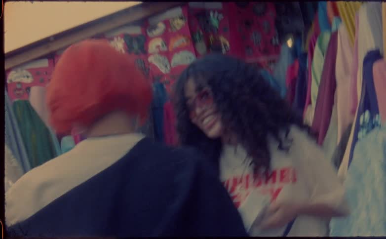 Two teenager girls laugh as they hold material at a shop on the street