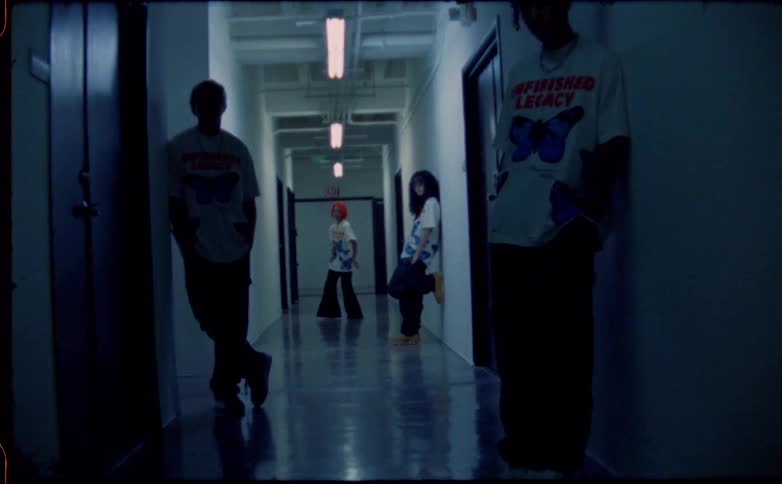 A teenage girl dances at the end of a hallway while three people lean against the walls and the lights flash on and off