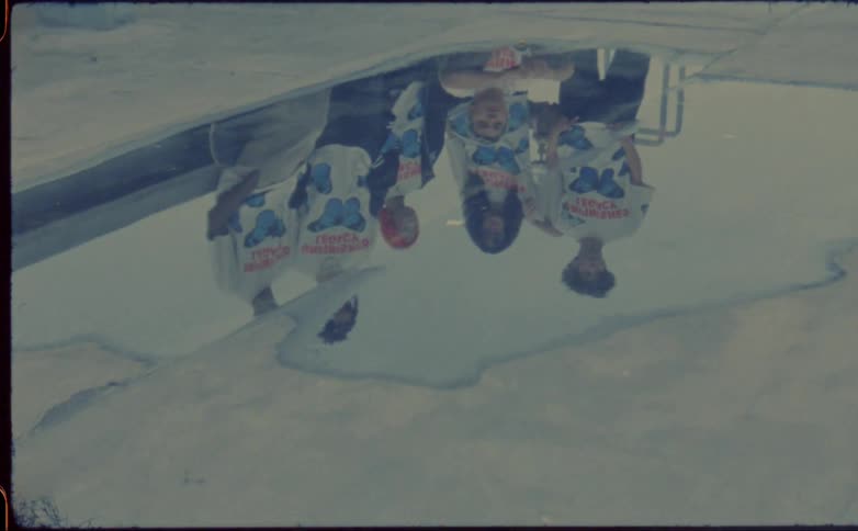 Group of people wearing the same tshirt are reflected in puddle on concrete